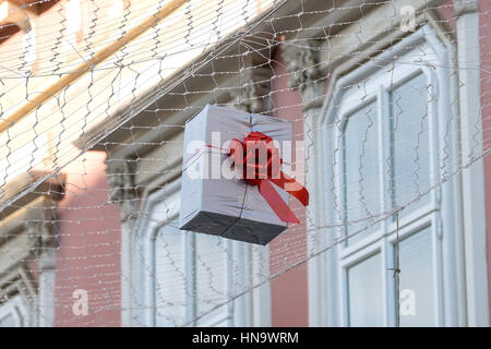 Gift boxes that hang suspended on wires and networks. Street decorations before Christmas, New Year and Valentine's Day. Stock Photo