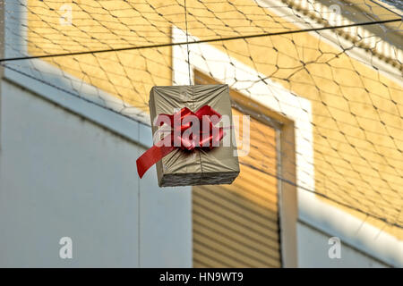 Gift boxes that hang suspended on wires and networks. Street decorations before Christmas, New Year and Valentine's Day. Stock Photo