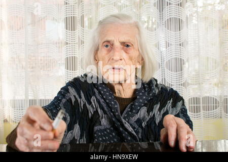 Senior woman smoking a cigarette at home Stock Photo