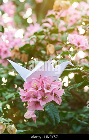 white paper crane on nature blurred garden background Stock Photo