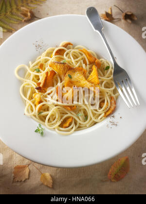 Wild organic chanterelle or girolle Mushrooms (Cantharellus cibarius), sauteed in butter and herbs with spaghetti Stock Photo