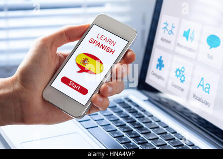 Learn Spanish language online concept with a person showing e-learning app on mobile phone with the flag of Spain Stock Photo