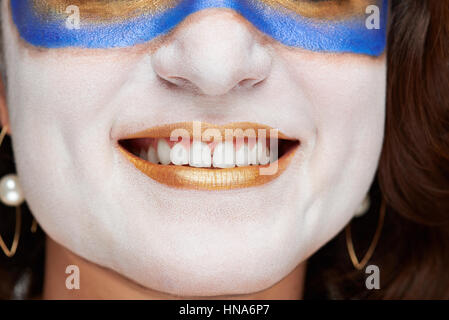 close up of woman smile with golden painted lips and white skin Stock Photo