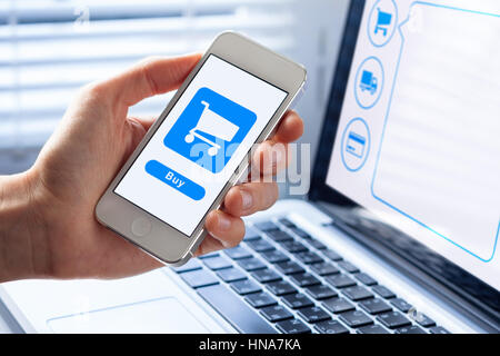 E-commerce or m-commerce concept with a person using a mobile phone to purchase online, shopping cart icon and a buy button on the interface Stock Photo