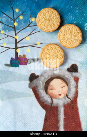 Three Golden Oreo biscuits on serviette with girl holding hands up, sandwich biscuits with a vanilla flavour filling Stock Photo