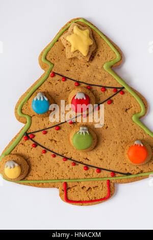 Large Iced Gingerbread Christmas Tree biscuit decorated with sweet baubles and iced star set on white background Stock Photo