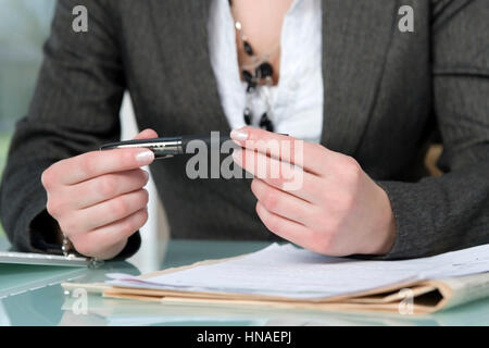 Geschaeftsfrau am Schreibtisch haelt Kugelschreiber in der Hand - businesswoman with ballpen in hands Stock Photo