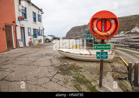 Fire assembly point and life belt at the harbour at Staithes, North Yorkshire,England,UK Stock Photo