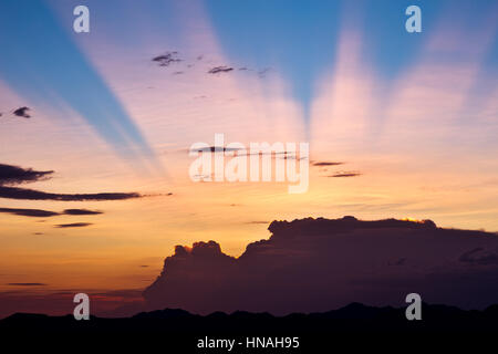 Anti-crepuscular sun rays shine from behind a storm at sunset. Stock Photo