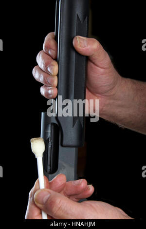 Gunsmith using swab to clean the inner rails of a pump action 20 gauge shotgun. Gun cleaning after each time out on the range or out hunting is an imp Stock Photo