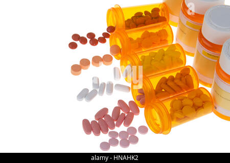 Many pills spilling out onto an isolated white background from orange medication bottles with row of prescription bottles lined up behind. Overwhelmin Stock Photo