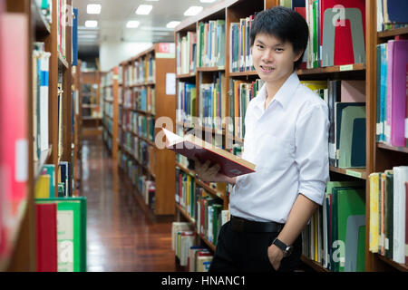 Asian student in uniform reading in the library at university Stock Photo