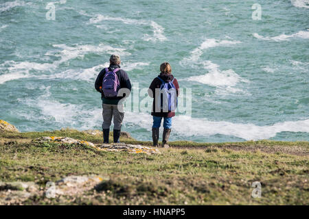 In Cornwall two walkers stand on Gwennap Head and look out over the sea. Stock Photo
