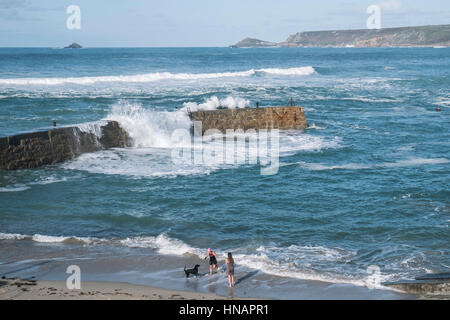High winds drive waves over the top of the breakwater in Sennen Cove, Cornwall, England. UK Weather. Stock Photo