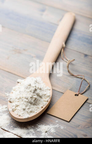 heap of white flour in wooden spoon on table with label for text. Stock Photo
