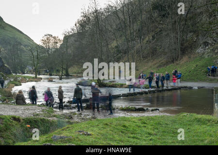 STEPPING STONES (DOVEDALE), PEAK DISTRICT, UK - DECEMBER  27 2016: Tourists crossing the busy stepping stones, Peak District, Derbyshire. Stock Photo