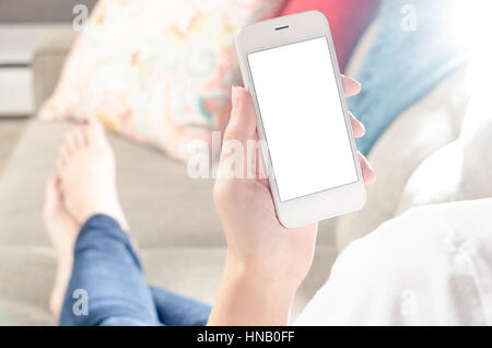 Female person at home on couch looking at smartphone with blank white screen Stock Photo