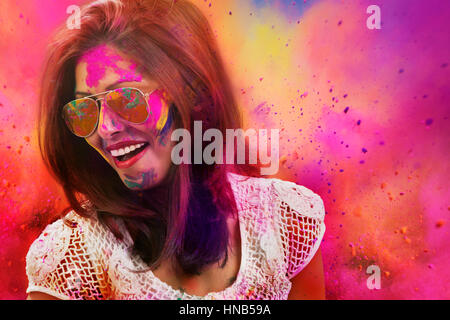 Portrait of a smiling girl with mirror sunglasses covered with colorful Gulal powder during a Holi festival Stock Photo