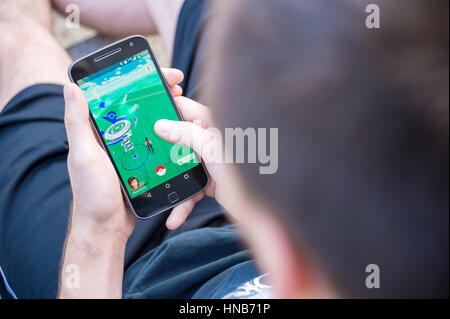 Montreal, CA - August 7, 2016: Closeup of a young man playing Pokemon Go on a smart phone. Pokemon Go is a virtual reality game released in July 2016. Stock Photo
