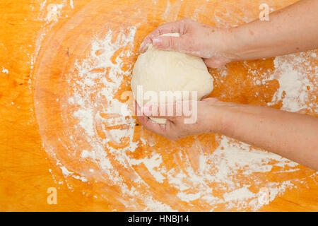 Female kneads dough on table with flour Stock Photo