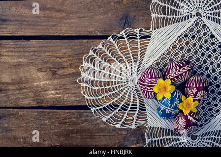 Hand-painted easter eggs, colorised, on the wooden table and embroidered napkin Stock Photo