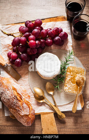 cheese board and wine. cheese, grapes, wine, honey and bread on a wooden table Stock Photo