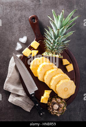 ripe sweet pineapple sliced on a cutting board and knife. stone gray background Stock Photo
