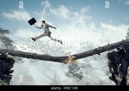 Young successful businessman jumping over gap. Risk and challenge concept Stock Photo