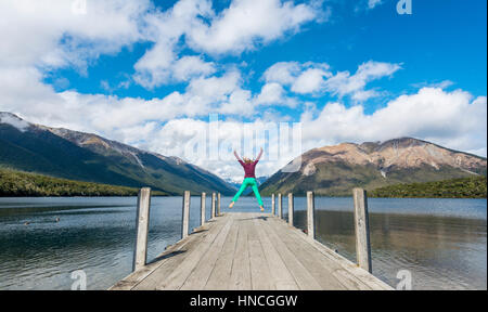 Woman jumping in the air, dock on Lake Rotoiti, Nelson Lakes National Park, Tasman District, Southland, New Zealand Stock Photo