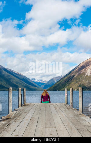 Woman sitting on dock, view of Lake Rotoiti, Nelson Lakes National Park, Tasman District, Southland, New Zealand Stock Photo