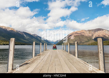 Woman sitting on dock, view of Lake Rotoiti, Nelson Lakes National Park, Tasman District, Southland, New Zealand Stock Photo