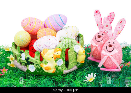Easter decoration with colorful eggs in basket and bunnies on artificial grass. Stock Photo