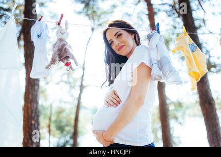 woman hanging baby clothes in linen rope outdoors Stock Photo