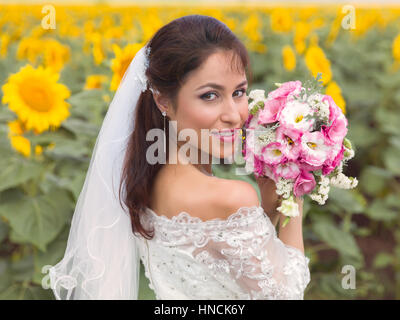 Beautiful young bride posing in a sunflower field Stock Photo