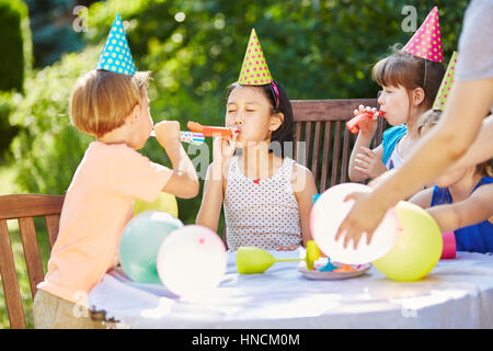 Kids having fun and celebrating with balloons at birthday party in garde Stock Photo