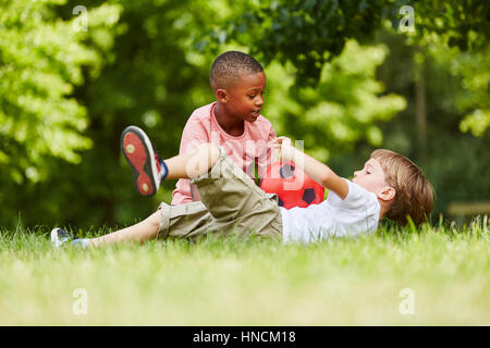 Two boys playing soccer together in the park in summer Stock Photo