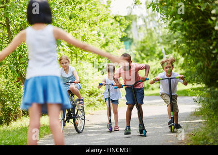 Children at bike and scooters race in the park in summer Stock Photo