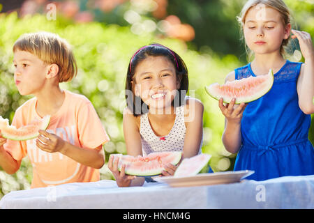 Girl eating healthy watermelon with friends in summer Stock Photo