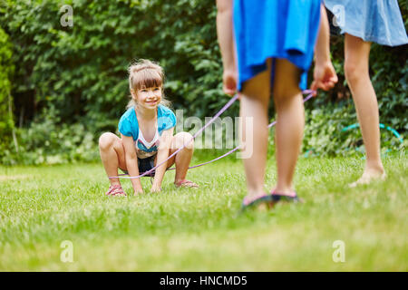 Kids play chinese jump rope game with rubber band in garden Stock Photo