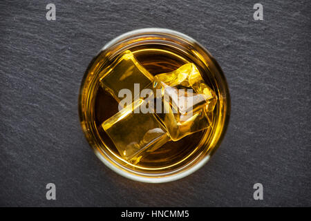 Round glass of whiskey with ice on a black background shot from above Stock Photo