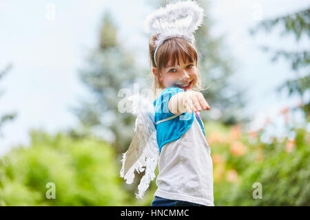 Girl with wings and angel costume has fun in garden Stock Photo