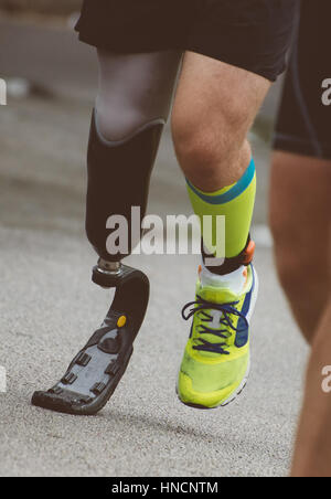 Man running with prosthetic leg on the street. Stock Photo