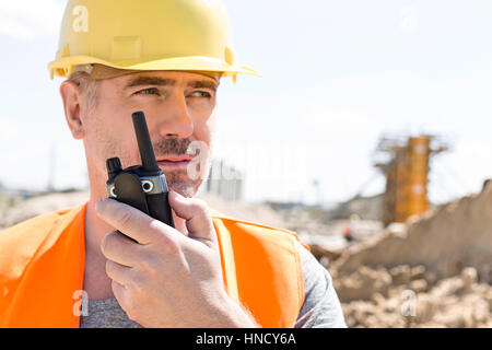 Confident supervisor using walkie-talkie at construction site Stock Photo