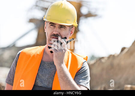 Confident supervisor using walkie-talkie at construction site Stock Photo