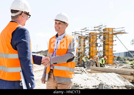 Engineers shaking hands at construction site against clear sky Stock Photo