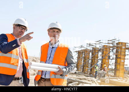 Male engineers discussing at construction site against clear sky Stock Photo