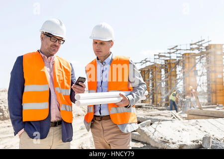 Male engineers using mobile phone at construction site against clear sky Stock Photo
