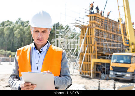 Supervisor writing on clipboard at construction site Stock Photo