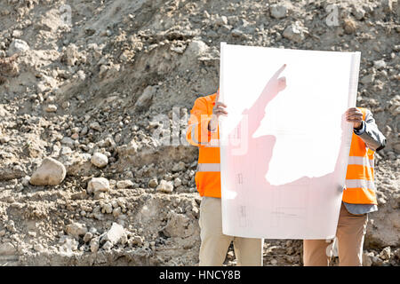 Engineers examining blueprint at construction site Stock Photo