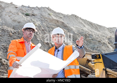 Engineers discussing over blueprint at construction site Stock Photo